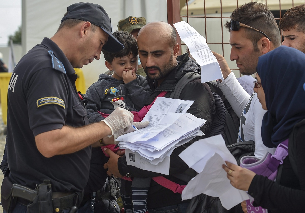 Gevgelija, 2015. szeptember 16. Görögország felõl Macedóniába érkezett illegális bevándorlók papírjait ellenõrzi egy rendõr egy regisztrációs táborban, a görög határ mellett fekvõ Gevgelija közelében 2015. szeptember 16-án. (MTI/EPA/Georgi Licovszki)