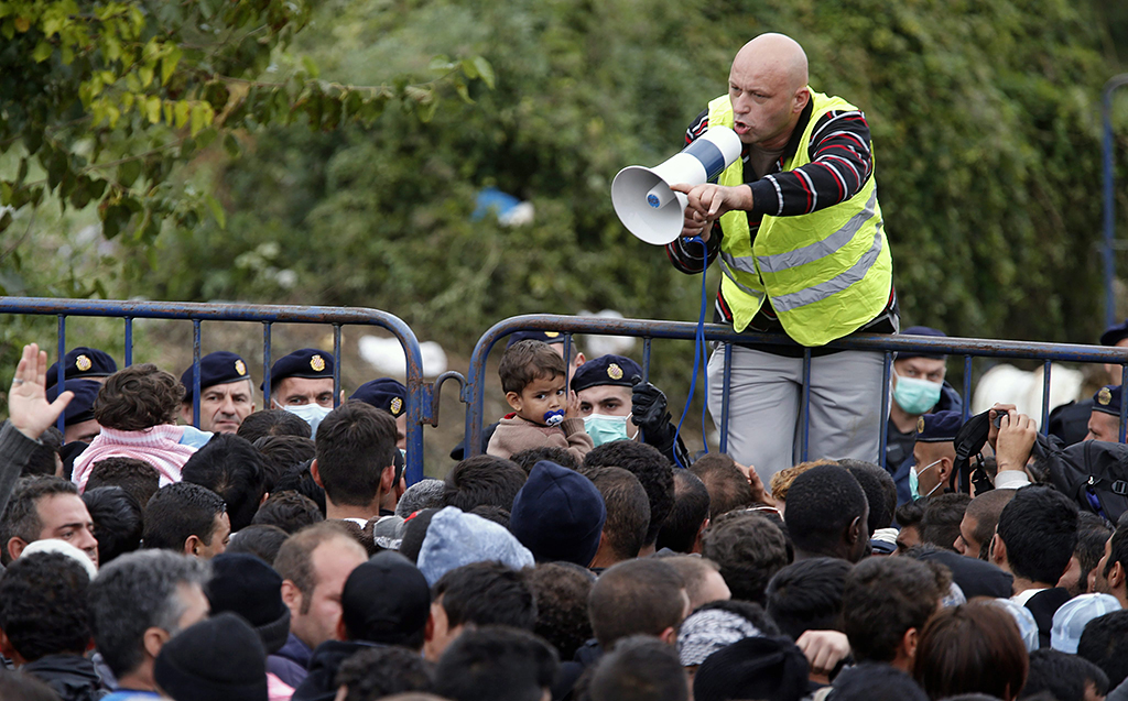 Berkasovo, 2015. szeptember 26. Egy férfi hangosbemondóval a kezében a fémkordonra mászva köszönti a horvátországi belépésre várakozó illegális bevándorlókat a szerbiai Berkasovóban 2015. szeptember 25-én. (MTI/EPA/Antonio Bat)