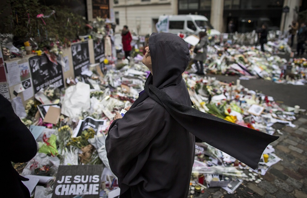 Párizs, 2015. január 13. Egy asszony imádkozik az áldozatok emlékére elhelyezett virágok és gyertyák a Charlie Hebdo francia szatirikus hetilap párizsi szerkesztõsége közelében 2015. január 13-án. Az elmúlt napokban Franciaországban elkövetett terrorcselekményekben 17 ember vesztette életét. (MTI/EPA/Ian Langsdon.)