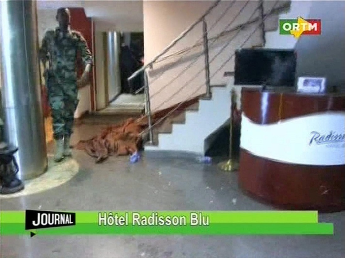 Tv-felvétel egy letakart holttest mellett elhaladó katonáról a Radisson Blu szállodában Fotó: MTI/AP