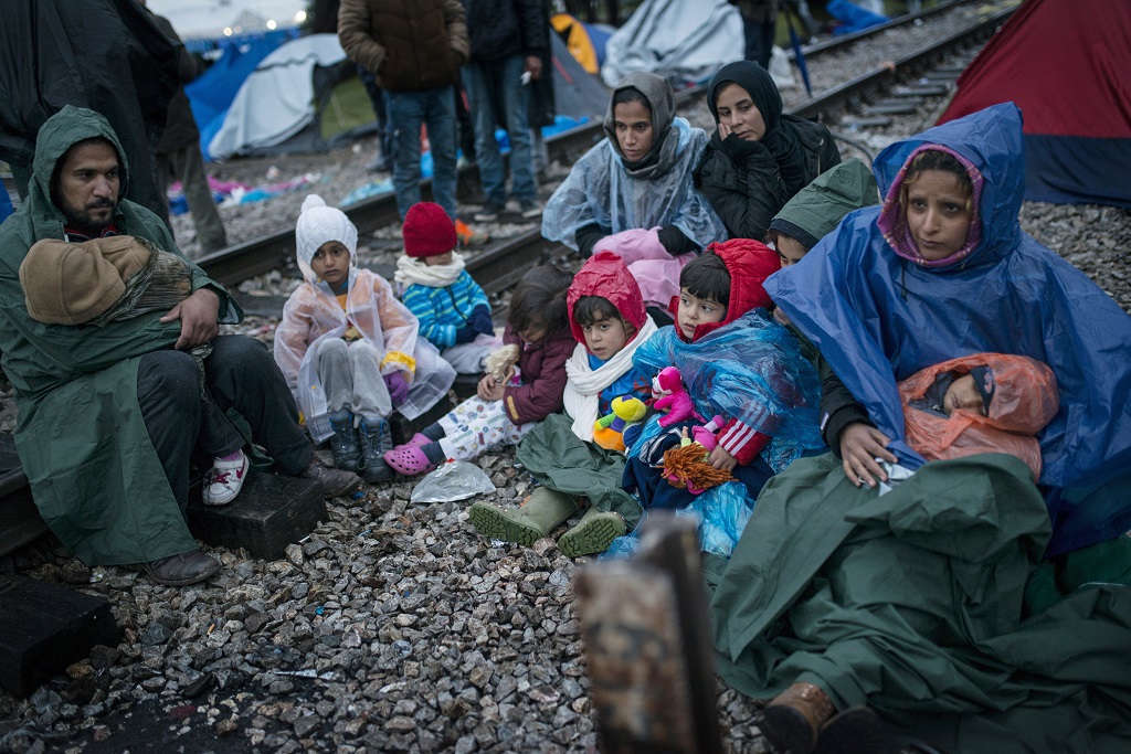 Iránból elmenekült emberek várnak a továbbindulásra az esőben, a görög-macedón határon, november 27-én. (Fotó: Europress)