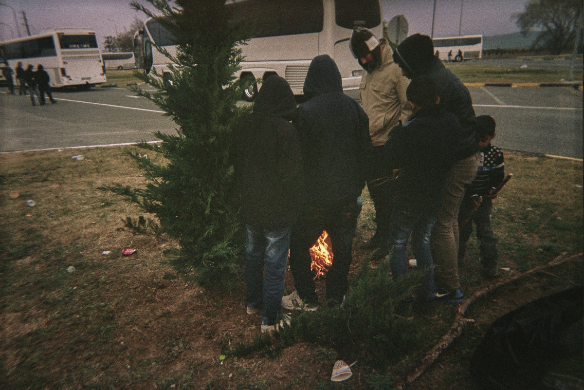 Refugees stand around a fire. Because the wood was wet, they burned trash and their last clothes to keep themselves warm. They had to stay outside the buses.
