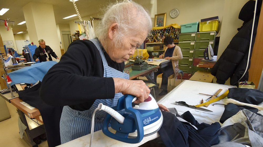 To go with AFP story "Japan-economy-employment-social" FOCUS by Daniel Leussink  In this picture taken on December 18, 2015, workers repair clothes at a seniors' work centre in Tokyo. Japan's silver-haired workforce is everywhere these days -- from wrinkled men waving glow sticks at construction sites to checkout counter clerks or caregivers for the very old. AFP PHOTO / Toru YAMANAKA / AFP PHOTO / TORU YAMANAKA