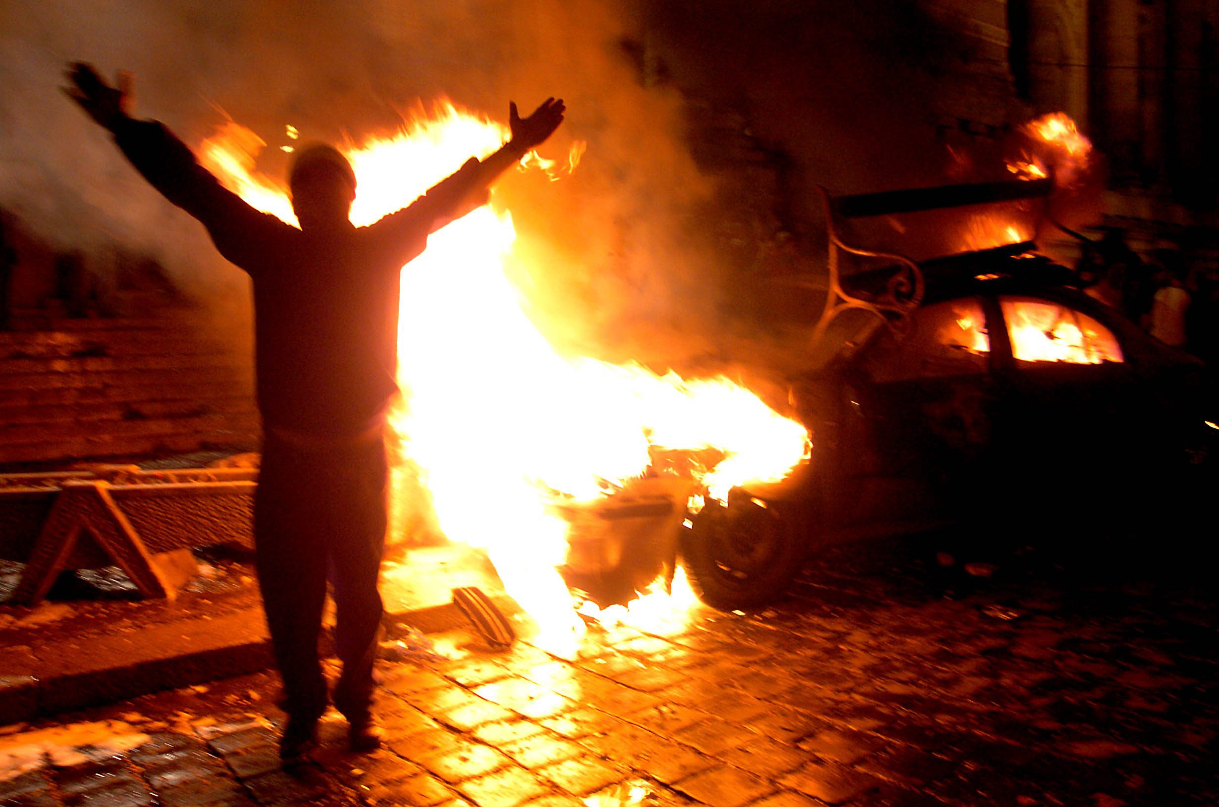Budapest, 2006. szeptember 19. Egy tüntetõ egy égõ gépkocsi elõtt a Magyar Televízió székházánál, amikor több mint ezer fiatal rohamozta meg az MTV épületét. MTI Fotó: Kovács Tamás