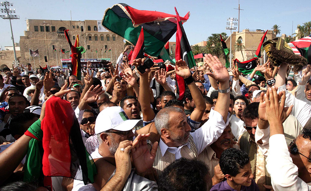 Tripoli, 2011. október 21. Líbiai zászlókkal ünnepelnek férfiak a Mártírok terén, a líbiai fővárosban,Tripoliban. Előző nap a líbiai Átmeneti Nemzeti Tanács (ÁNT) harcosai elfogták a líbiai fővárostól, Tripolitól 360 km-re keletre fekvő Szirt környékén Moammer el-Kadhafi volt líbiai vezetőt, aki életét veszítette az akció során. Kadhafi temetését későbbre halasztották, mert az ENSZ emberi jogi főbiztosa szerint ki kell vizsgálni halálának körülményeit, hogy tisztázni lehessen, valójában harcban esett el, vagy elfogása után kivégezték. (MTI/EPA/Szabri Elmhedvi) 