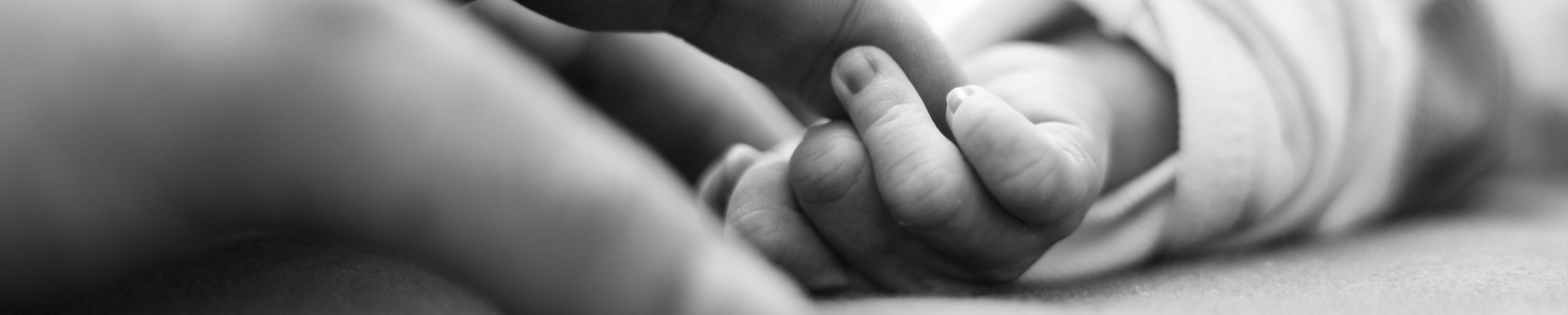 right after birth, baby is holding father's finger