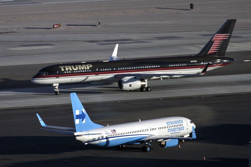 Republican presidential nominee Donald Trump's plane (TOP) passes Democratic presidential nominee Hillary Clinton's campaign plane at McCarran International Airport on October 18, 2016 in Las Vegas, Nevada, on the eve of the two candidates' third and final US presidential debate. / AFP PHOTO / Brendan Smialowski
