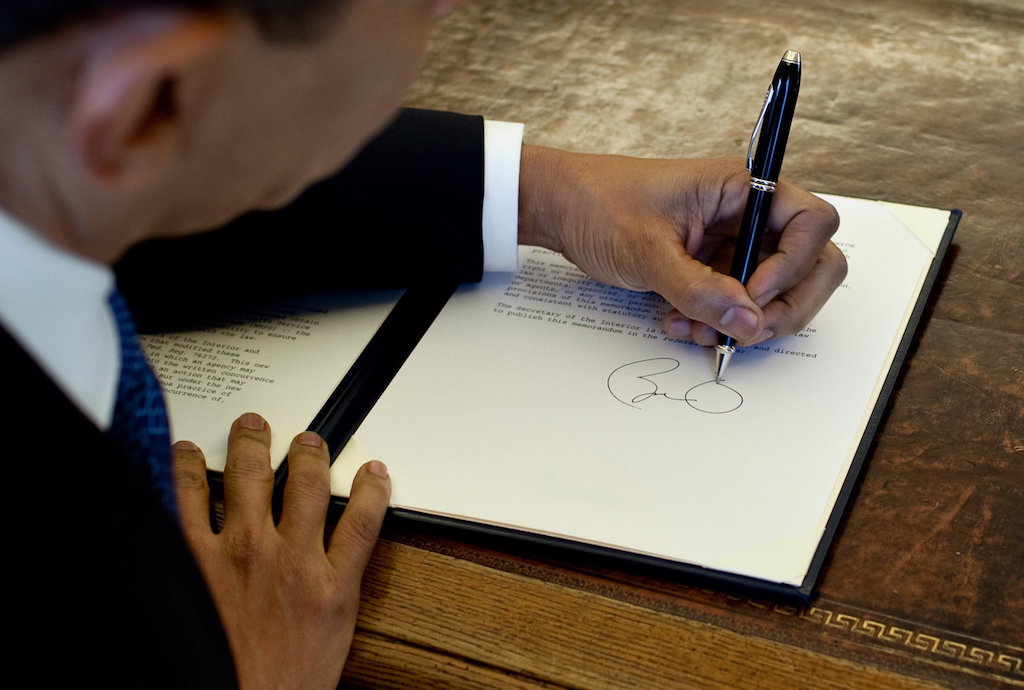 President Barack Obama writes at his desk in the Oval Office 3/3/09. Official White House Photo by Pete Souza