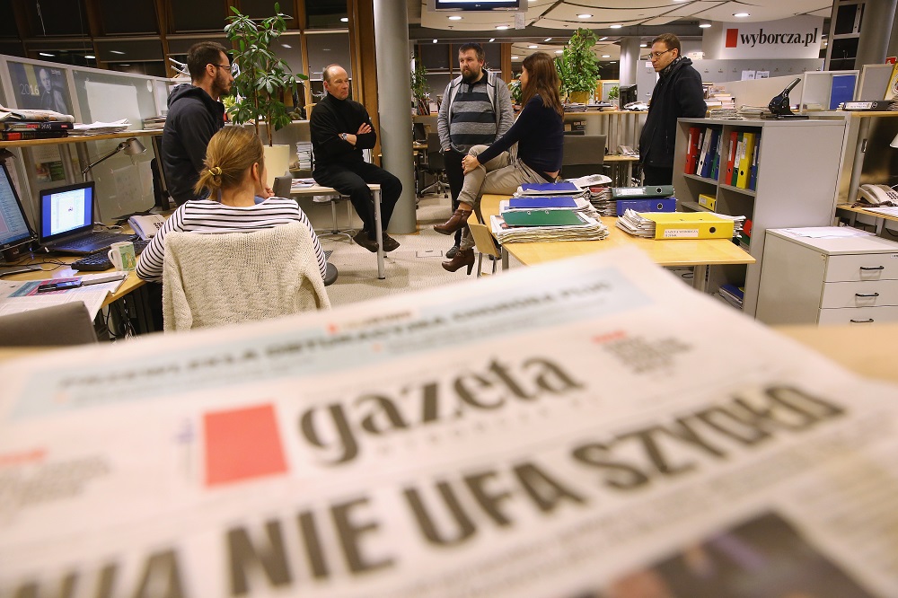 WARSAW, POLAND - FEBRUARY 26: Piotr Stasinski (C-L, in black), Deputy Editor-in-Chief of Polish independent daily newspaper Gazeta Wyborcza, speaks with editorial colleagues in the newsroom of the paper near a copy of Gazeta Wyborcza whose headline reads: "The EU Distrusts Szydlo", in reference to new Polish Prime Minister Beata Szydlo, on February 26, 2016 in Warsaw, Poland. Independent media in Poland currently face a new, uncertain political atmosphere with the conservative and populist Law and Justice (PiS) political party, led by Jaroslaw Kaczynski, having won elections last year and appointing President Andrzej Duda and Prime Minister Beata Szydlo. Since taking office PiS legislators have curtailed the power of the Constitutional Court and removed critical journalists from state-owned media. Stasinski says critics charge Gazeta Wyborcza is too anti-PiS and hence too partisan, though he says the paper's strident role is crucial in defending democracy in Poland under the new government. (Photo by Sean Gallup/Getty Images)