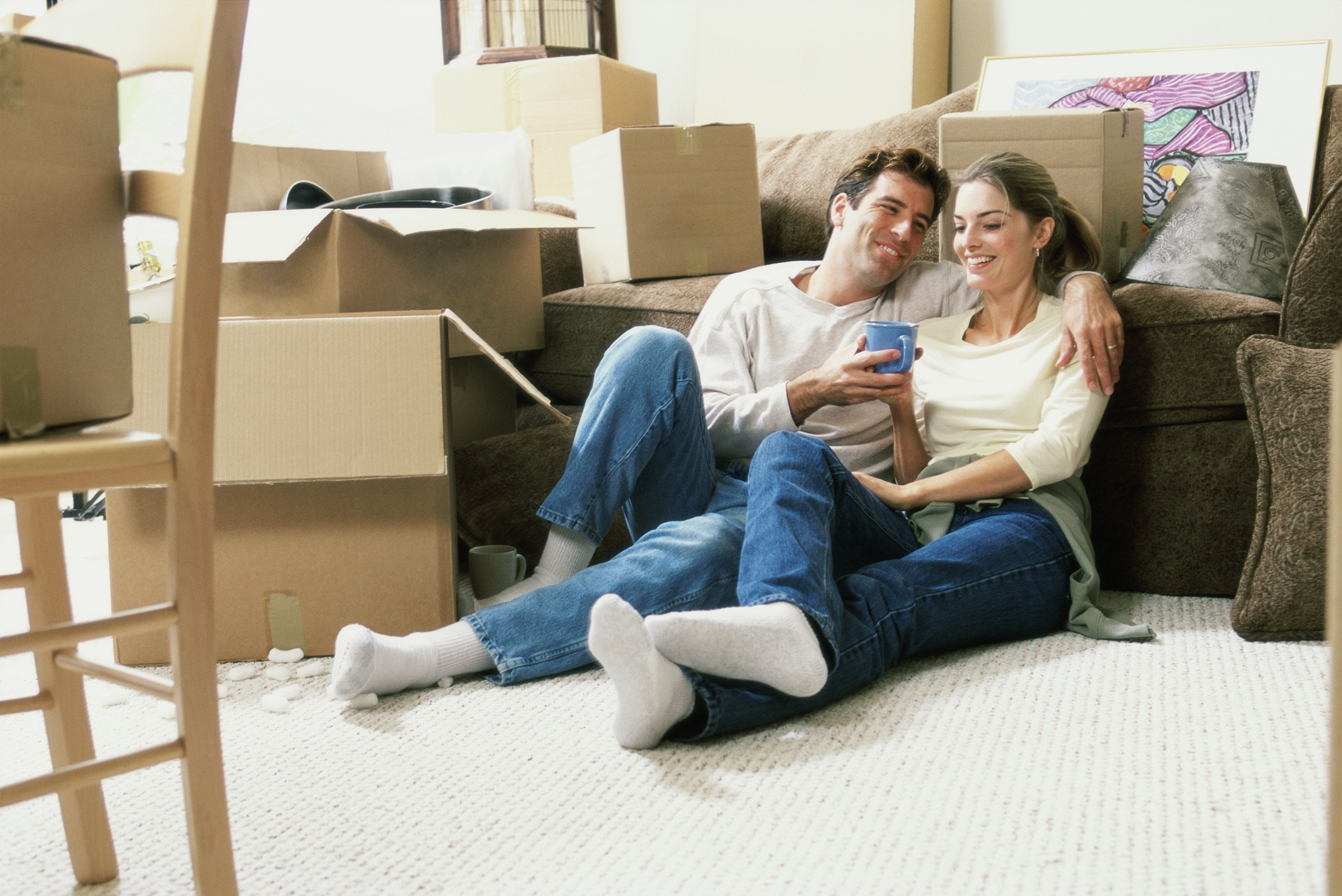 Young couple holding a coffee cup sitting on the floor