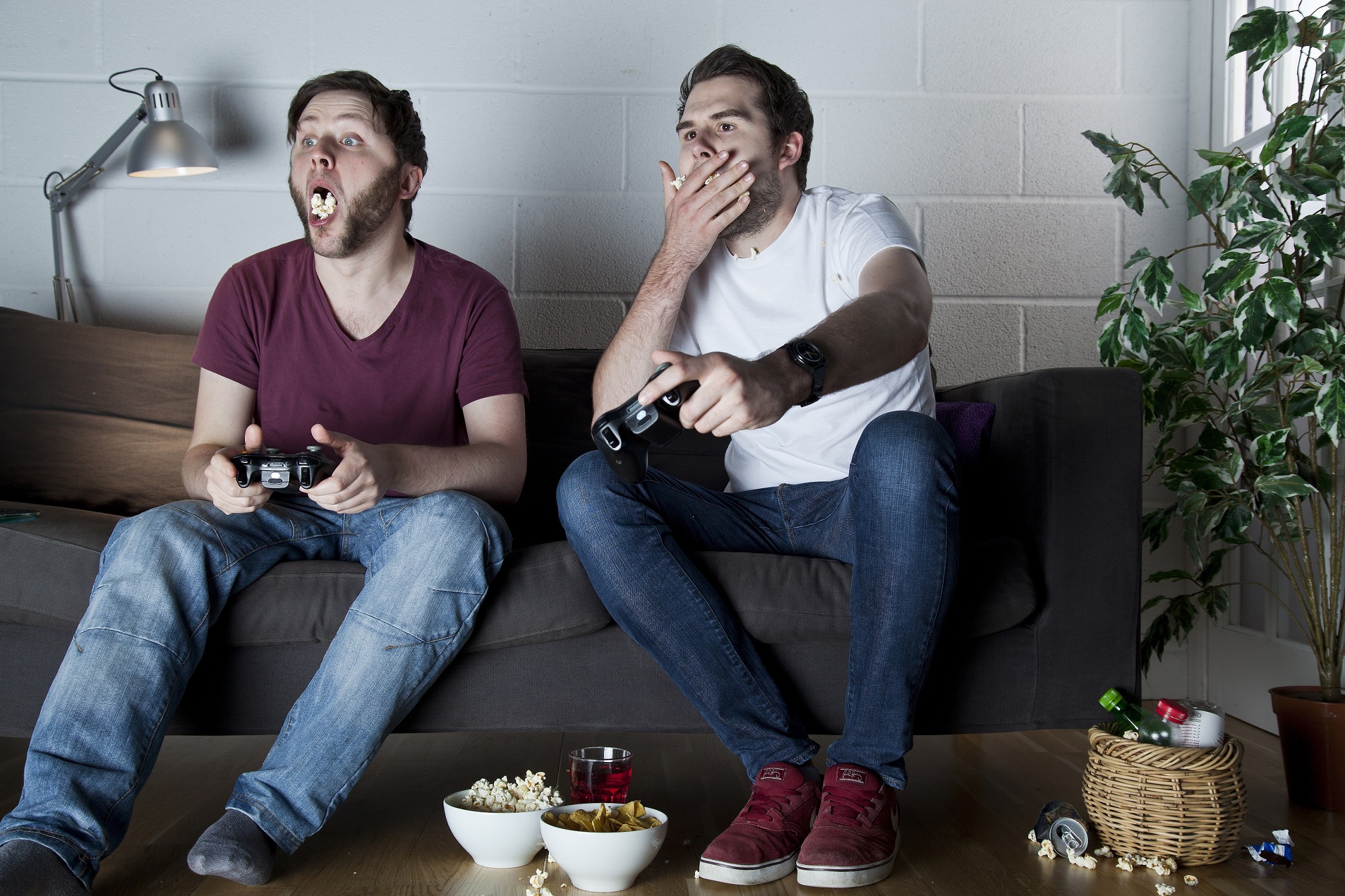 Two young men eating popcorn while playing Sony PlayStation 3 video games on a sofa, taken on July 9, 2013. (Photo by Philip Sowels/Future Publishing via Getty Images)