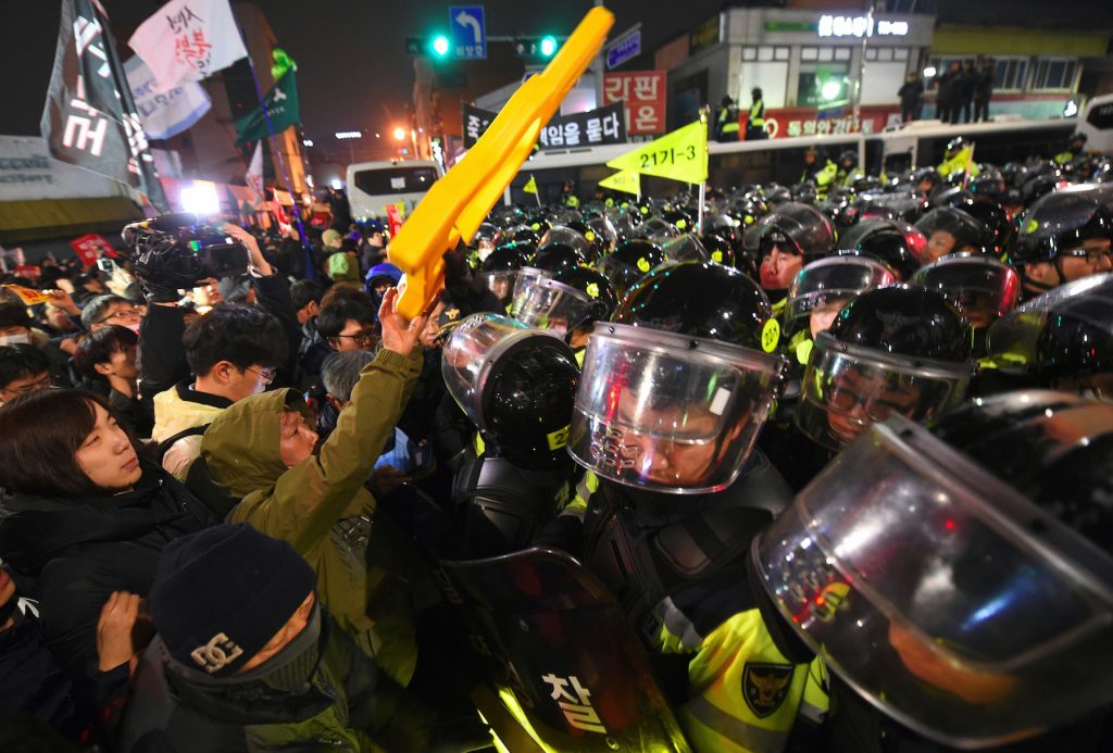 Riot police troops and protesters engage in a shoving match as the protesters attempt to march toward the presidential Blue House during an anti-government rally demanding the resignation of South Korea's President Park Geun-Hye in central Seoul on November 26, 2016. Up to 1.3 million protesters braved sleet and freezing temperatures in Seoul on November 26 to demand Park resign over a corruption scandal or face impeachment, organisers said.  / AFP PHOTO / JUNG YEON-JE
