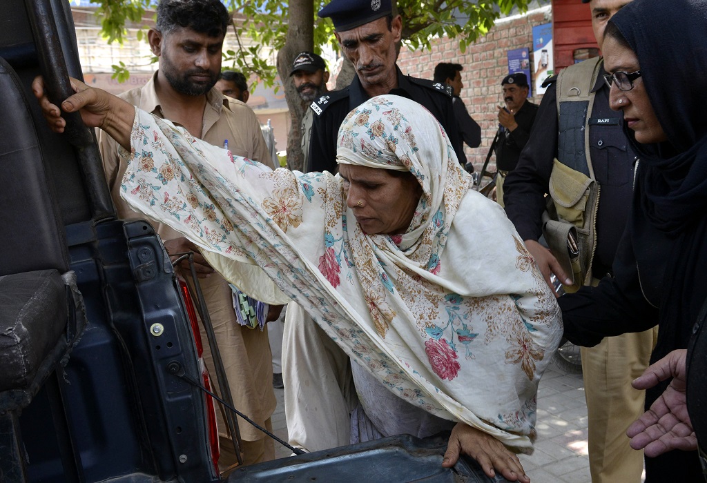 Pakistani police escort Perveen Bibi (C), who allegedly killed her own daughter by burning her alive, as they go to local court in Lahore on June 10, 2016. Pakistani teenager Zeenat Bibi was burnt alive by her mother on June 8 after marrying a man of her own choice, police said, the latest in a string of so-called "honour killings" in the country. / AFP PHOTO / ARIF ALI