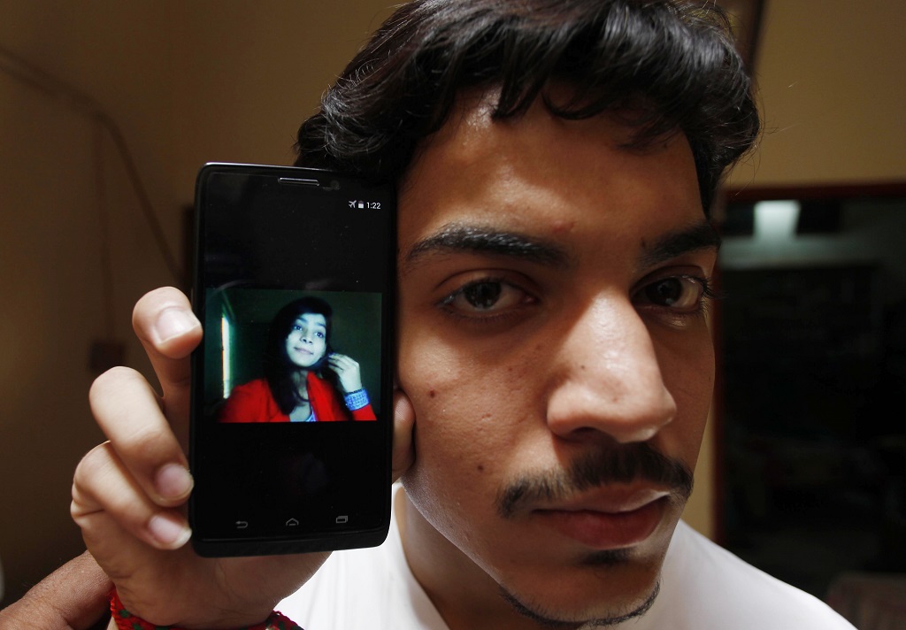 Hassan Khan shows the picture of his wife Zeenat Bibi, who was burnt alive by her mother, on his cellphone at his residence in Lahore on June 8, 2016. A Pakistani mother burnt her 16-year-old daughter alive for marrying a man of her own choice, before running out into the street to tell neighbours she killed the teenager for dishonouring the family. / AFP PHOTO / STR