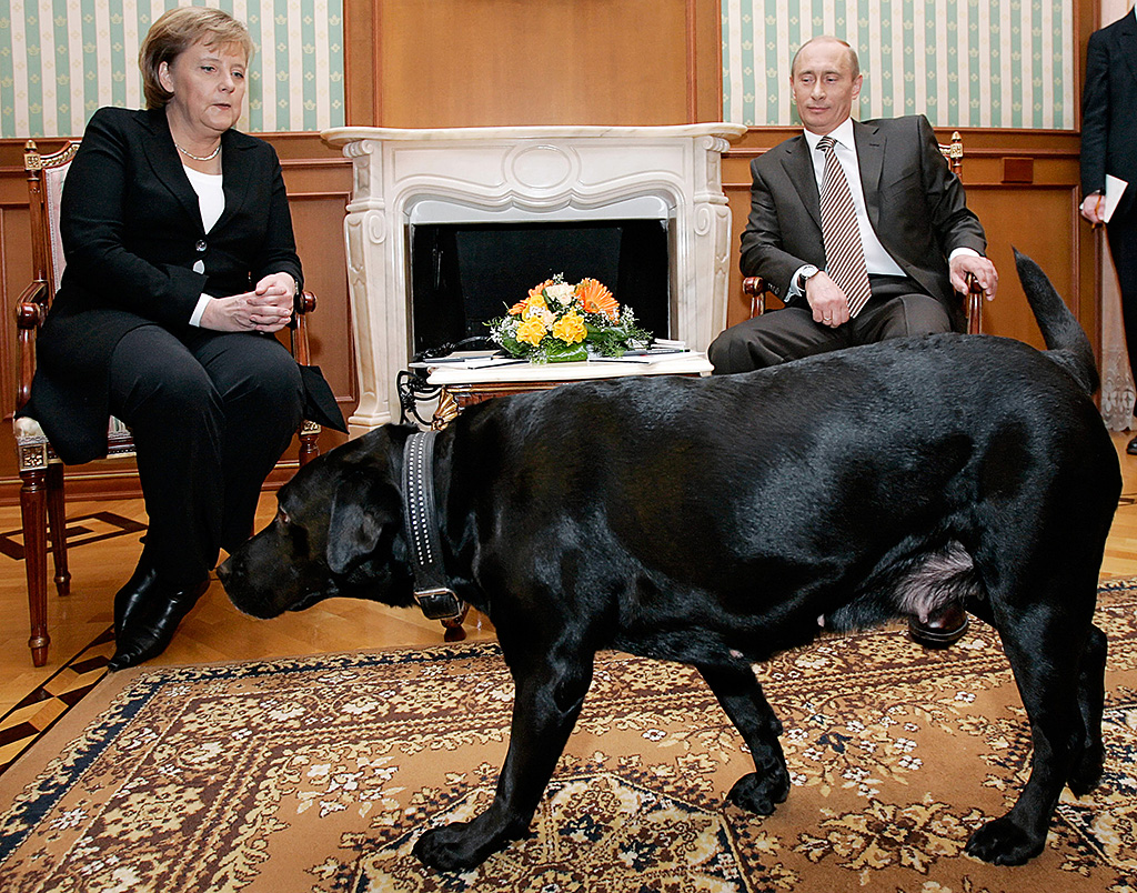 Russian President Vladimir Putin (R) and German Chancellor Angela Merkel are watched by Putin's dog Koni as they address journalists after their working meeting at the Bocharov Ruchei residence in Sochi, 21 January 2007. German Chancellor Angela Merkel arrived here for talks with President Vladimir Putin expected to focus on securing guarantees for energy supplies to the European Union, a Kremlin official said. AFP PHOTO / PRESIDENTIAL PRESS SERVICE / ITAR-TASS / AFP PHOTO / ITAR-TASS / DMITRY ASTAKHOV