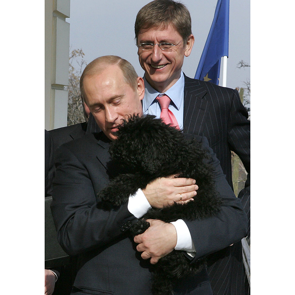 Russian President Vladimir Putin hugs a Hungarian 'Puli' dog owned by Hungarian Prime Minister Ferenc Gyurcsany (background)) and his wife Klara Dobrev (out of camera range) as they stand on the balcony of the Prime Minister residence in Budapest, 01 March 2006. Putin is on a two-day official visit aimed at boosting cooperation between both countries. AFP PHOTO POOL / PRIME MINISTER OFFICE / MIKLOS DER / AFP PHOTO / POOL / MIKLOS DER