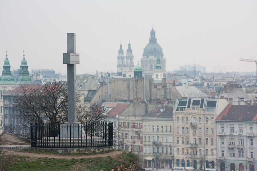 A Belvárosi plébániatemplom (balra), és a Szent István-bazilika kupolája, illetve tornyai a Gellérthegyen álló kereszt hátterében (Fotó: Vincze Miklós/24.hu)
