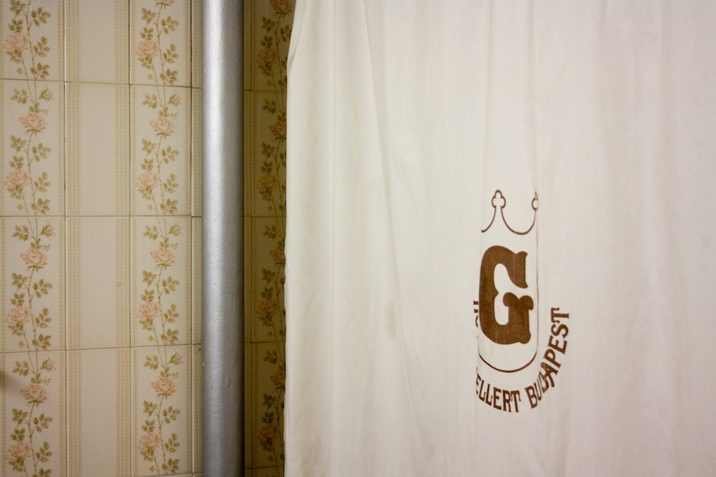 A fürdőszoba részlete a hotel egykori logójával díszített zuhanyfüggönnyel (Fotó: Vincze Miklós/24.hu)