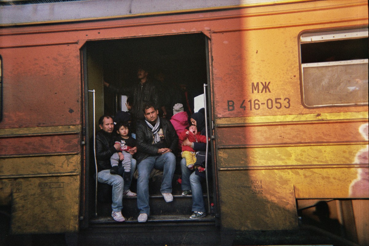 Refugees looking out a overcrowded train in Macedonia. On the rigtht a mother holds her crying kid in her arms. The doors were not able to close and have been open during the drive.