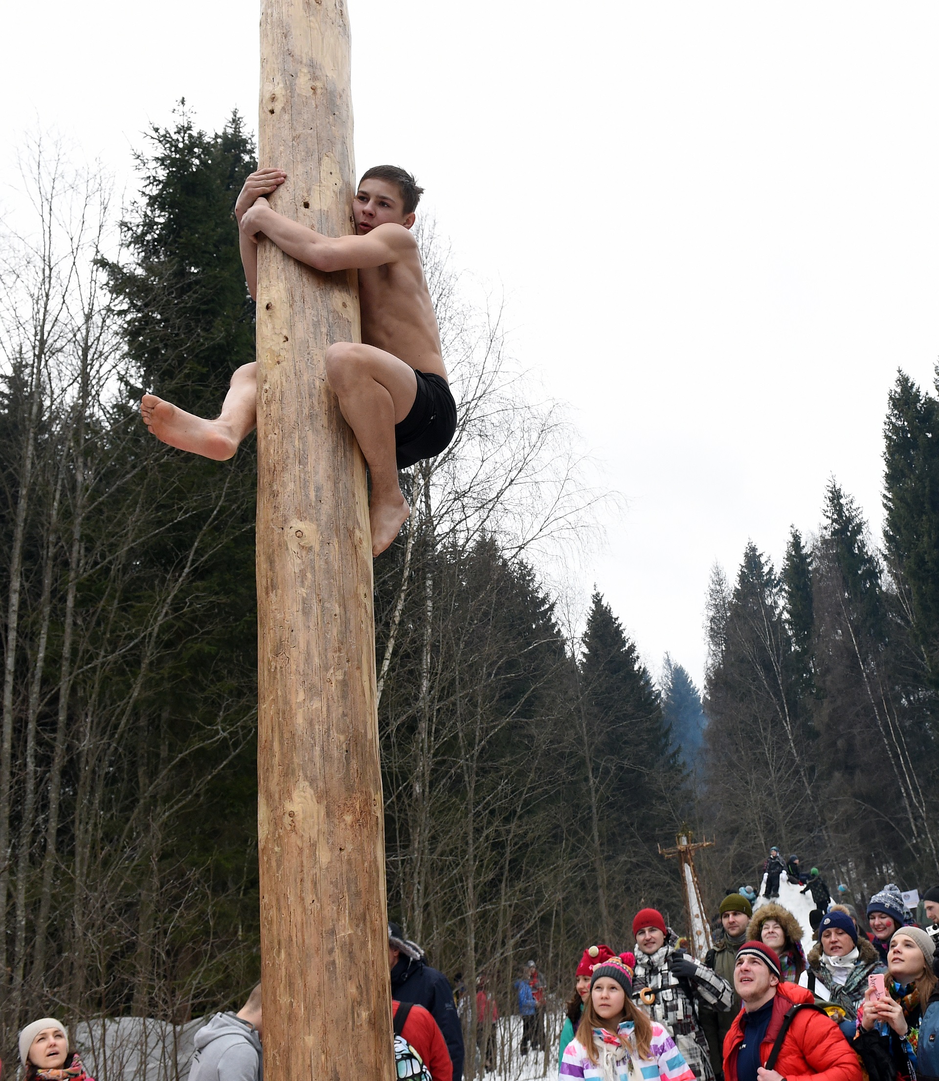 Young man competes in the pole-climb game close to the village of Abramtsevo, 60 km north of Moscow on March 13, 2016, in celebration of Maslenitsa (Shrovetide), a farewell ceremony to winter. Shrovetide precedes the beginning of Lent, with each day of the week holding its own meaning. Shrove Sunday, also known as the Sunday of Forgiveness, is a day for asking forgiveness for the harm caused to other people intentionally or unintentionally. / AFP PHOTO / VASILY MAXIMOV