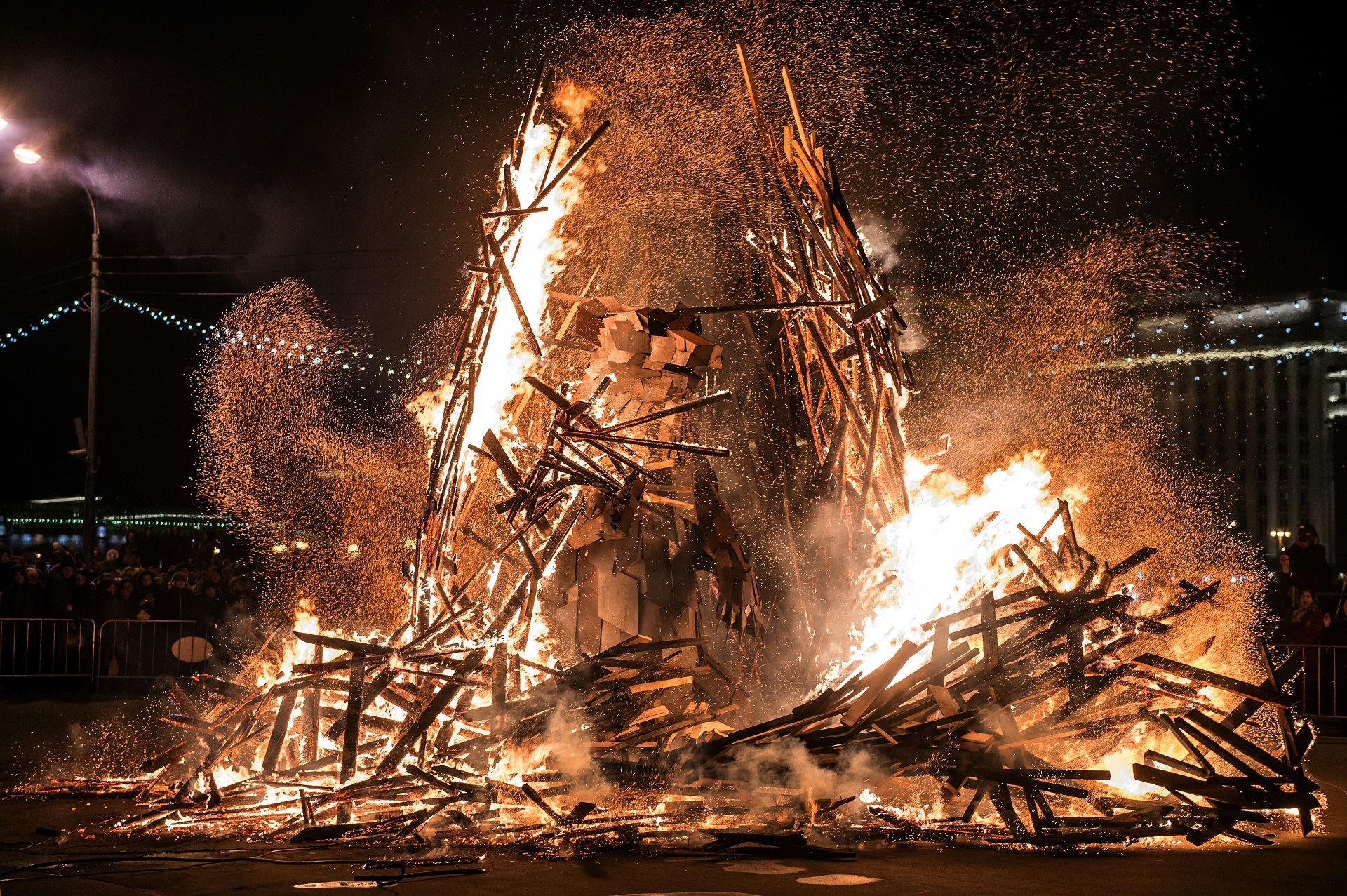 People watch a berloga («the lair») dummy with 3,5-meter steel bear inside burning down during celebrations of Maslenitsa (Shrovetide), a farewell ceremony to winter in Moscow's Gorky Park on March 13, 2016. Hungarian artist Gabor Miklos Szoke made a bear as the symbol of spring, and in march its time to wake him up and get him out of the lair. The art installation consists of two parts: the lair, which will be burnt together with winter and the bear, which will stay at the Park with spring. / AFP PHOTO / DMITRY SEREBRYAKOV