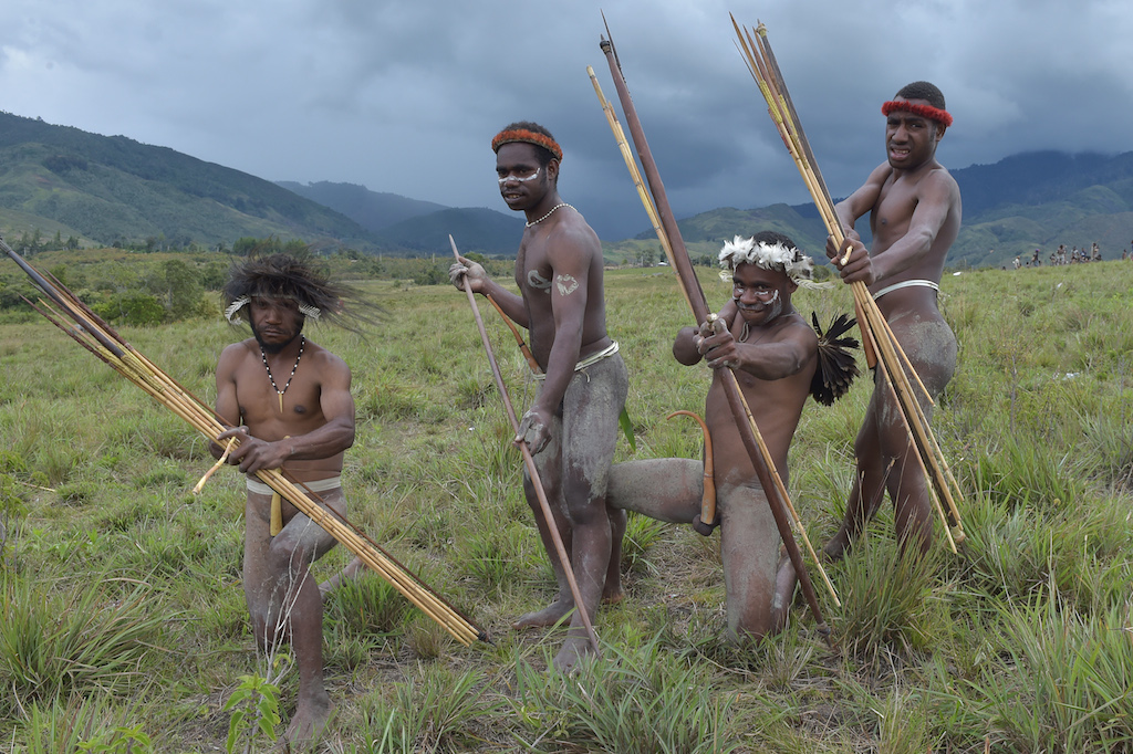 Dani tribesmen pose for photographs prior to performing a mock tribal war battle during the 27th annual Baliem Valley Festival in Walesi district in Wamena, Papua Province on August 9, 2016. Performances at the 27th Baliem Valley Festival, taking place from August 8 to 10, feature mock battles of highland tribes of Dani, Yali and Lani to symbolise the high spirit and power that have been practised for generations. / AFP PHOTO / ADEK BERRY