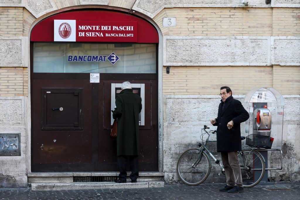 Customers queue to use an automated teller machine (ATM) outside a branch of Banca Monte dei Paschi di Siena SpA bank after the Italian vote on constitutional reform referendum in Rome, Italy, on Monday, Dec. 5, 2016. Banca Monte dei Paschi di Siena SpA shares seesawed on Monday after Prime Minister Matteo Renzis decision to resign added to uncertainty about the banks plans to raise as much as 5 billion euros ($5.3 billion) in capital by the end of the year. Photographer: Chris Ratcliffe/Bloomberg via Getty Images