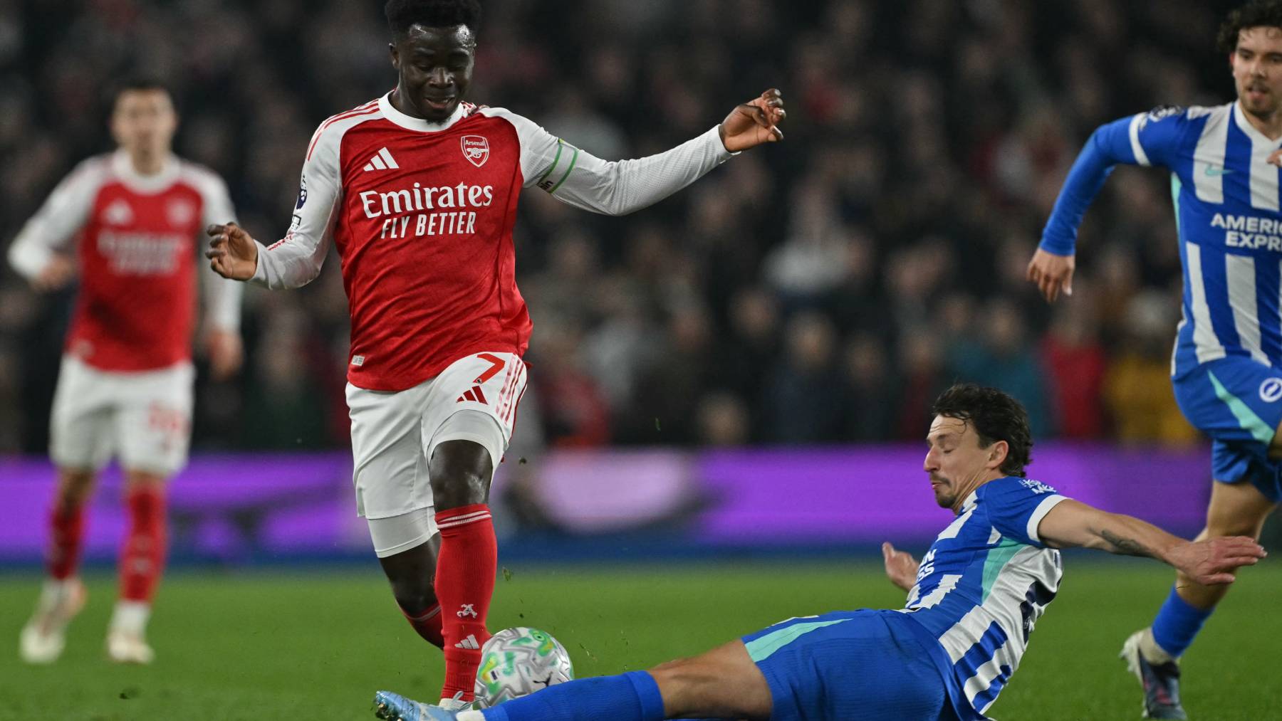 Brighton's French defender #21 Olivier Boscagli (R) tackles Arsenal's English midfielder #07 Bukayo Saka (2L) during the English Premier League football match between Brighton and Hove Albion and Arsenal at the American Express Community Stadium in Brighton, southern England on March 4, 2026.