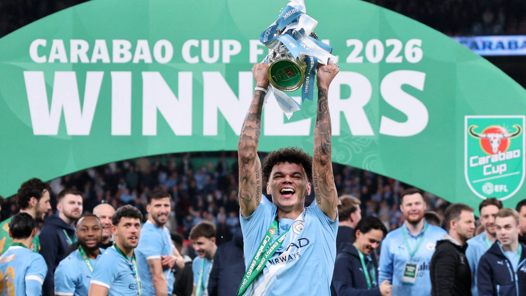 Manchester City's English midfielder #33 Nico O'Reilly poses with the trophy as City players celebrate after the English League Cup final football match between Arsenal and Manchester City at Wembley Stadium in London on March 22, 2026. Nico O'Reilly scored both goals as City won the game 2-0.